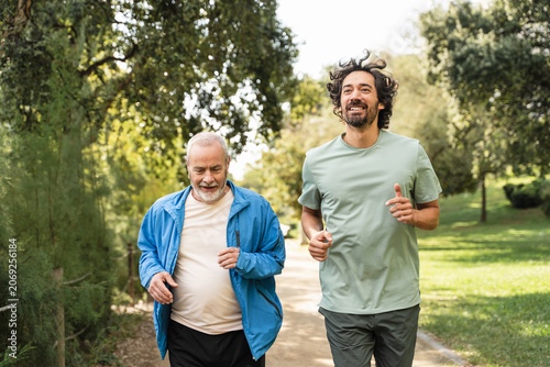 Senior dad man jogging doing sport together with his son, running for healthy lifestyle and family bonding