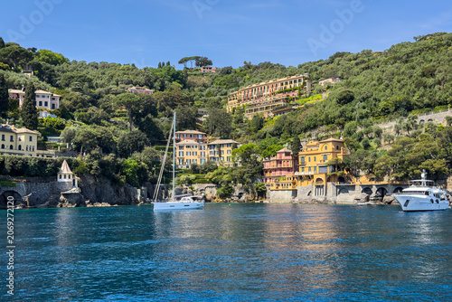 Luxury yachts moored in the blue waters facing the green hills of Portofino, Liguria region, Italy