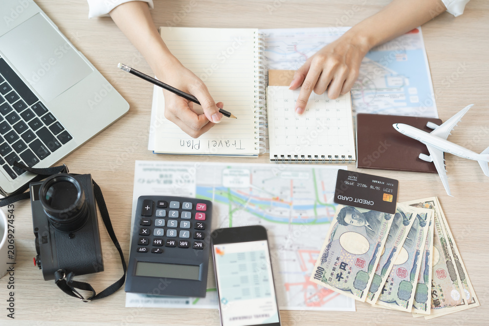 Naklejka premium Travel planning, vacation, holiday trip concept, asian young tourist woman hand take note to check travel date on calendar and information for booking hotel online, ticket preparing for journey trip.