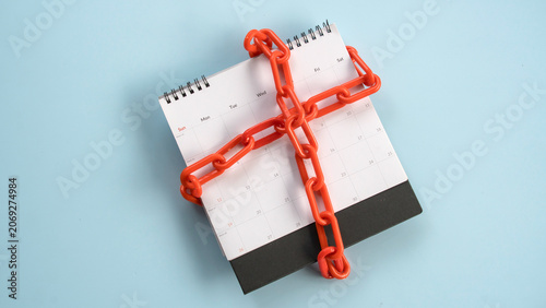 Canvastavla An overhead shot of a spiral desk calendar wrapped tightly in an red plastic chain, conceptualizing time restrictions or locked schedules