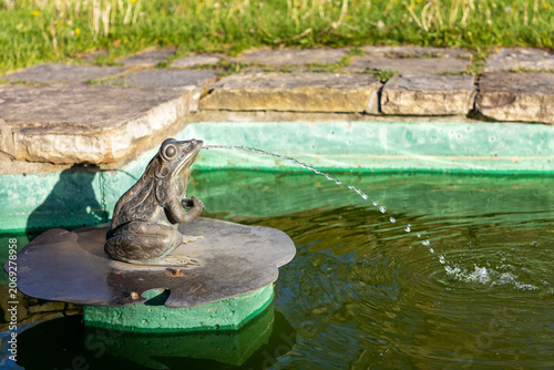 Bronze frog fountain spraying water into pond in Ornamental Gardens in Ottawa, Canada