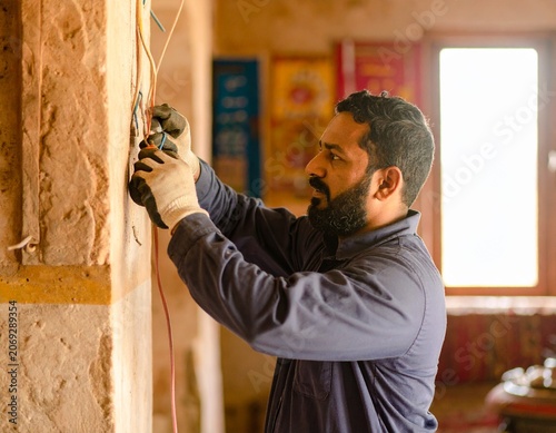 Skilled Indian electrician working on electrical infrastructure, following safety regulations and industry best practices.