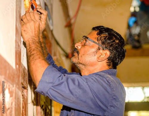 Industrial Indian electrician ensuring safe electrical operations with helmet, gloves, safety shoes, and insulated equipment.