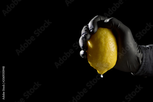 Obraz na plátně Hand in black glove squeezing last drop from lemon concept of extreme margin squ