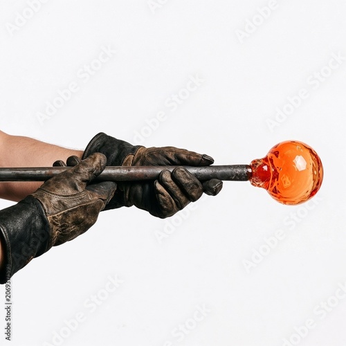 Glassblower shaping molten glass with metal rod and protective gloves  