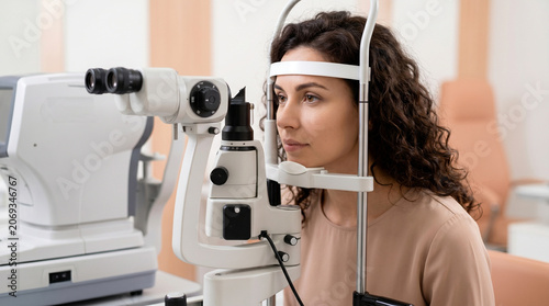 Young woman undergoing eye examination with slit lamp microscope in modern ophthalmology clinic professional vision check and optometrist equipment