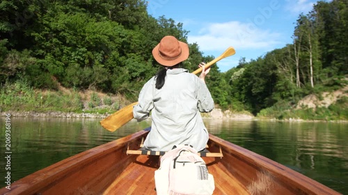 Female paddling canoe on forest lake