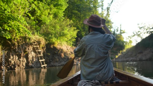 Rear view of woman canoeing on peaceful forest channel