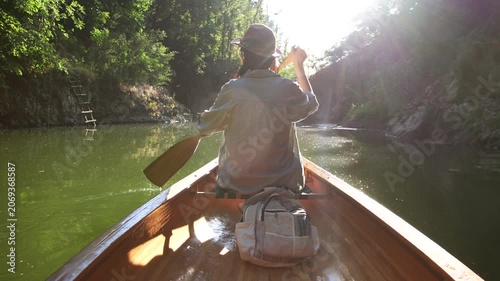 Woman paddling canoe through forest waterway