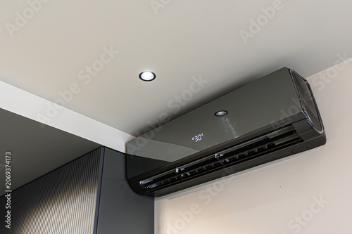 Tableau sur toile sleek dark-gray wall-mounted air conditioner displays 30° on its digital panel
