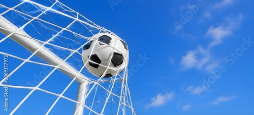 Soccer ball hitting the goal net against a bright blue sky