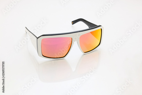 stylish sunglasses on a glossy white table, red orange glass, white sunglasses frame, yachting glasses, cycling glasses, reflection on a glossy surface