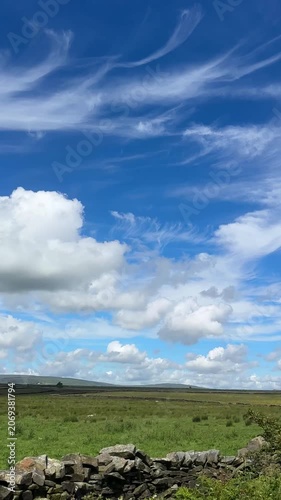 Vertical shot. Beautiful sky above Lancashire countryside. Cirrus clouds, stone wall by the rural road.