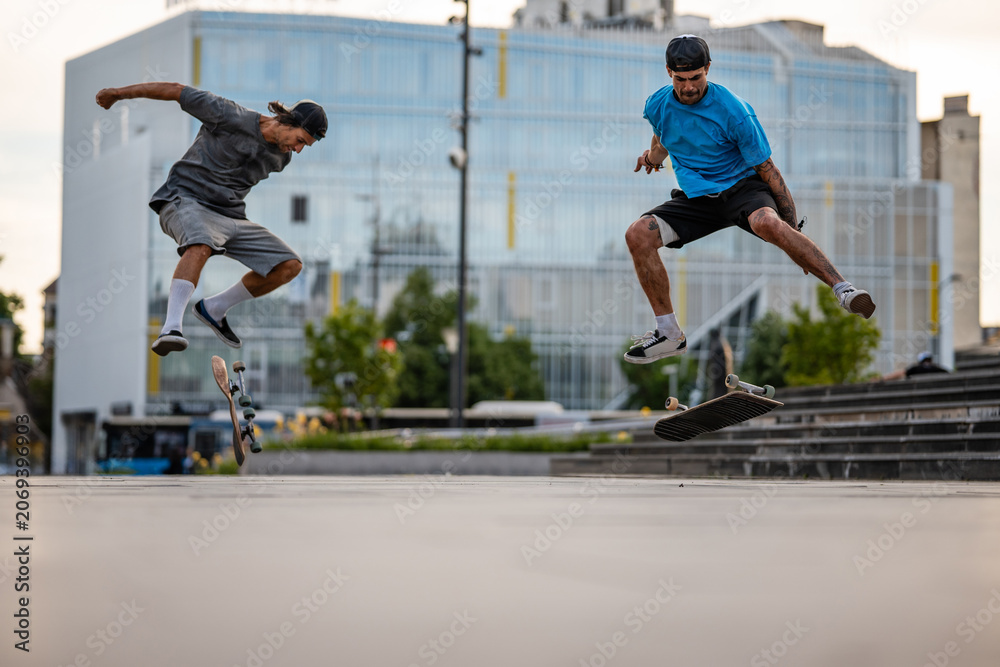 Εκτύπωση καμβά Skateboarders jumping mid-air performing dynamic kickflip tricks