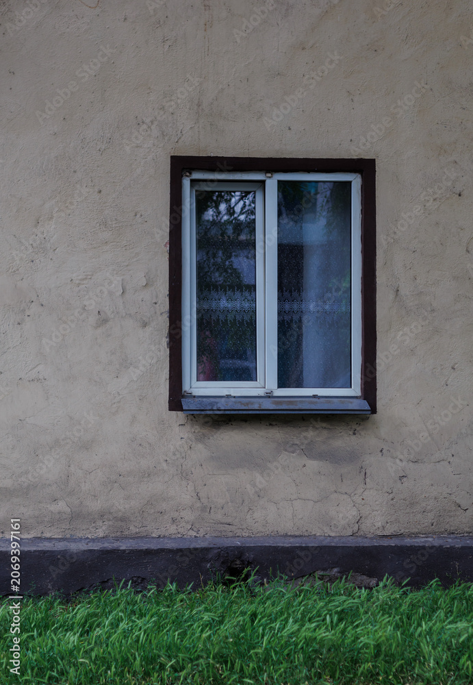 Fototapeta premium the wall of an old house with a window and green grass