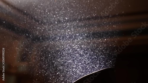 Fine dust particles suspended in air and illuminated by a strong spotlight against a dark background. Concept atmosphere, texture, lighting, theater, cinema, air quality, environment and abstract