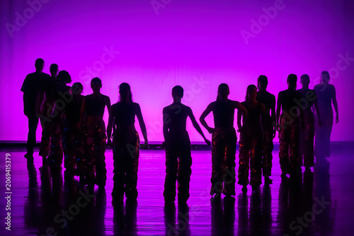 Group of dancers performing on stage in a bright purple silhouette