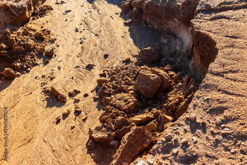 Фотография Close-up view of sandy soil erosion featuring loose rocks and sediment deposits