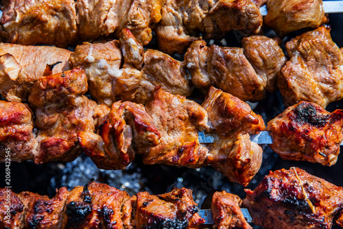 Foto Appetizing kebabs on skewers over charcoal in a barbecue grill in nature