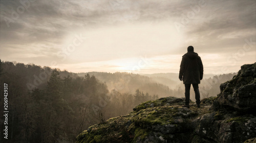 Solitary Person Overlooking Misty Forest Valley at Sunrise