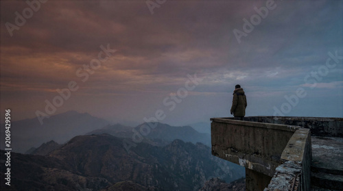 Solitary Person Overlooking Misty Forest Valley at Sunrise