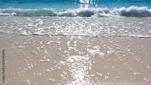 Gentle ocean waves wash over a pristine white sand beach
