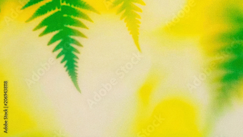 Green leaves create patterns on a bright yellow background in a natural setting