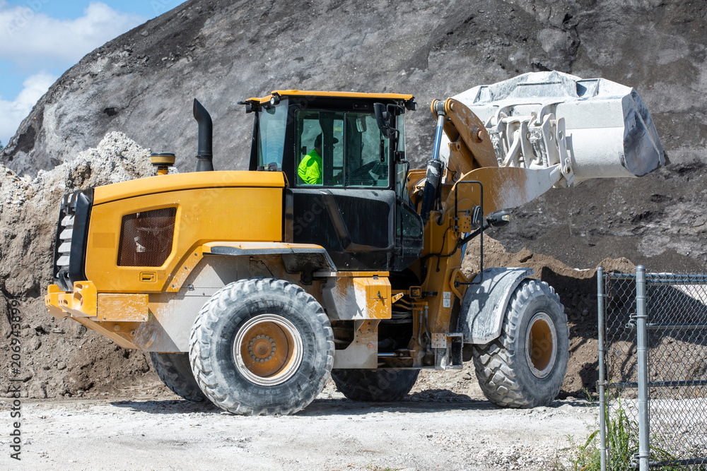 Fototapeta premium Yellow wheel loader carrying sand at a concrete batching plant