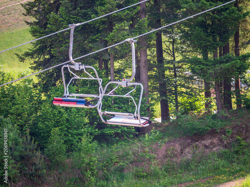 Canvas Print Empty chairlift passing above a forested hillside in summer