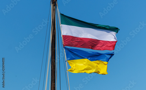 Italian and Ukrainian Flags Waving on Mast Against Blue Sky