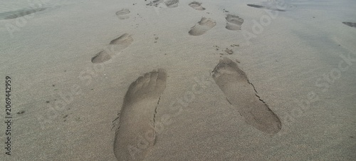 Human footprints walking on wet sand beach