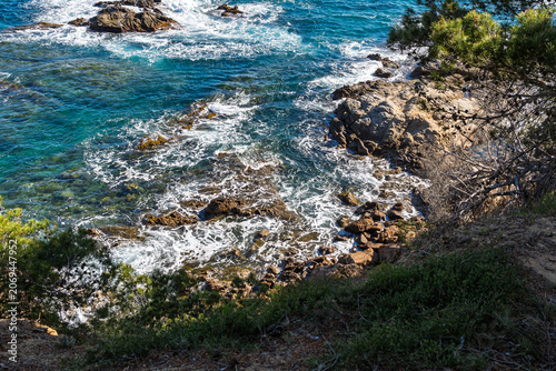 Fotografija Ocean waves crashing on rocky cala fenals coast