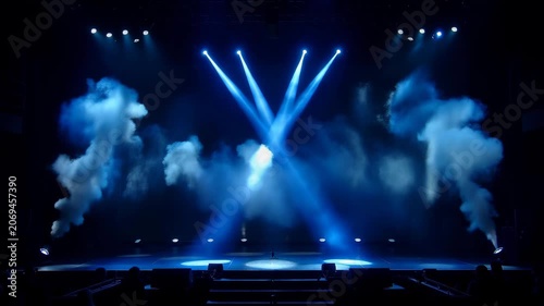 Bright blue stage spotlights flashing and cutting through thick white smoke in a dark concert hall. Concept of entertainment and live performance events