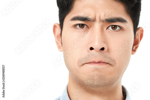 Tableau sur toile Serious young Asian man with furrowed brow and tense expression
