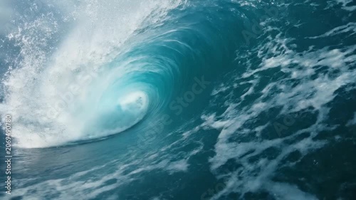 A massive blue ocean wave curls under a dramatic cloudy sky