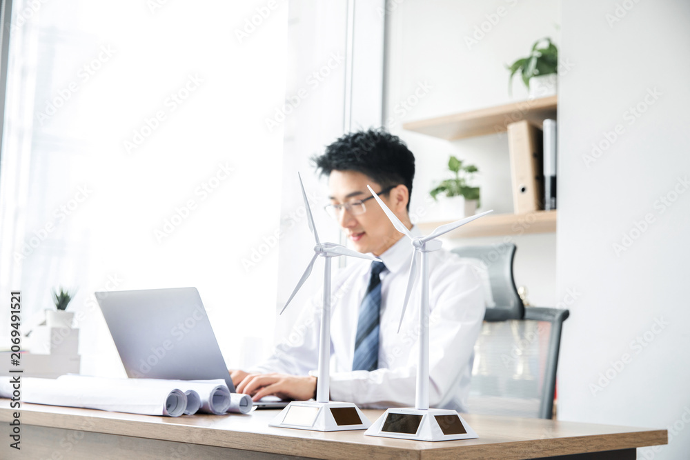 Fototapeta premium Businessman working with wind turbine models in modern office