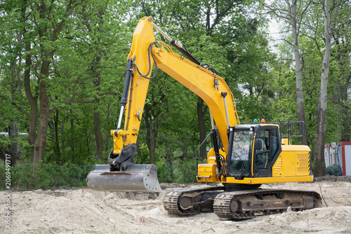 Crawler excavator with operator at work on a construction site during earthworks and site preparation, high key lighting