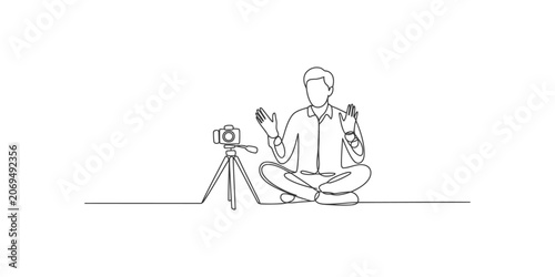 Obraz na plátně A man sitting in a meditative pose with a camera on a tripod isolated on white b