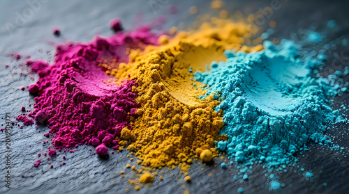 Bright colorful powder piles in pink yellow and blue on a dark wooden table showing vibrant festival pigment dust art design