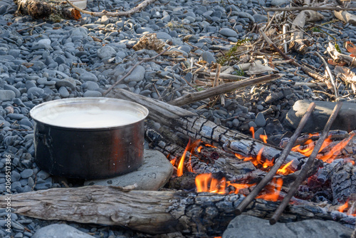 Photos Pot cooking lentils over backcountry fire | A pot of lentils simmers over an open campfire with rebar grate during a backcountry kayak expedition