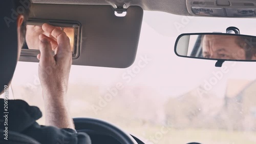 Driver’s hand on rearview mirror with reflection of his face, quiet concentration and introspective moment during drive, 4K