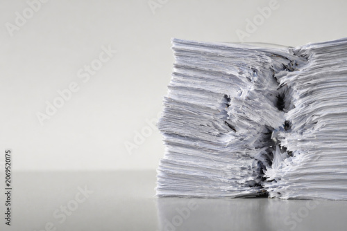 Damaged stack of paper documents on a light background. Space for text.