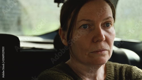Serious concerned woman riding in car, gazing through window during journey, 4K