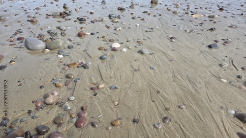 Konstfotografi Sandy pebble beach background texture with scattered stones on wet shore for coa