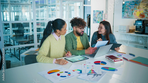 Dynamic view of startup team celebrating success. Male giving high five to female colleague. Woman raising hand with excitement. Holding tablet and laptop on desk. Achieving business goals.