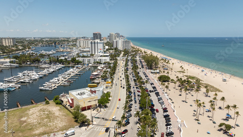 Aerial view captures the vibrant coastline of Fort Lauderdale Beach, where luxury high-rises, pristine white sand beaches, and turquoise Atlantic waters are complemented by yachts and boats