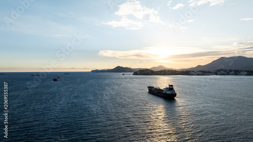 Foto Cargo Ship Sailing Through Manzanillo Bay at Sunset