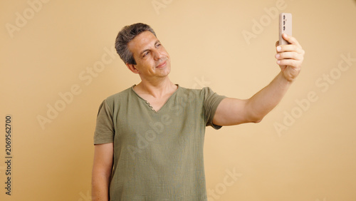 Foto Mature man standing and smiling while taking a self portrait using a mobile phon