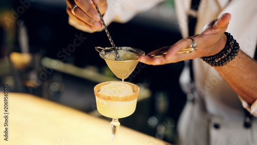 Quadro su tela Professional bartender preparing and serving an elegant craft cocktail with a la