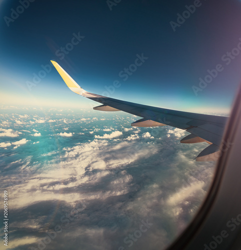  Vista de la ventana del avión: fondo de viaje del atardecer con nubes azules del océano. Vista a través de la ventana del avión sobre el océano y las nubes al atardecer. Concepto de viajes aéreos